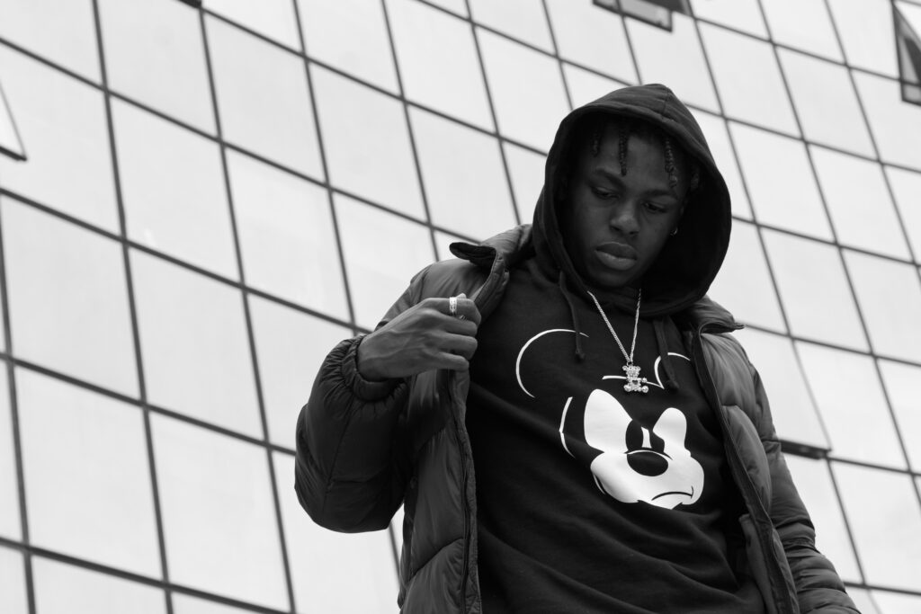 aymeric, jeune homme doudoune pull mickey et photo noir et blanc fond urbain vitré - série de photo portait en extérieur réalisée par Anael Jourdain Photographe Amateur Hauts-de-France