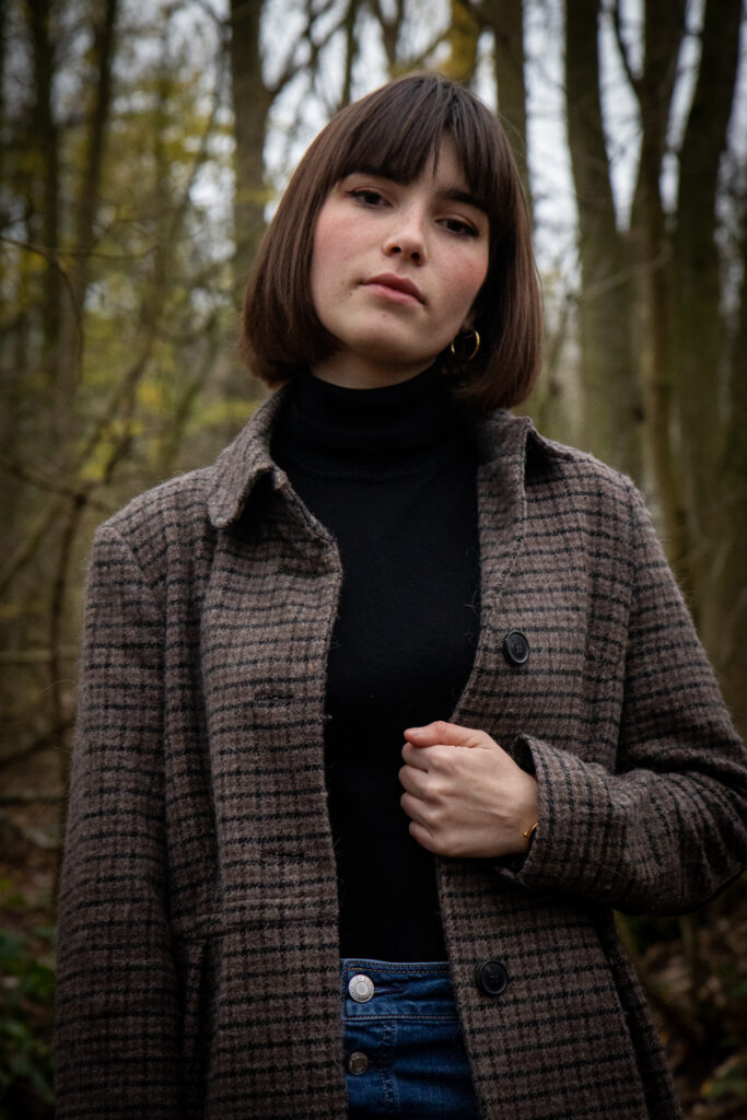 léa, photo portrait extérieur couleur, nature, forêt, veste carreaux, jean, carré frange, automne- série de photo portait réalisée par Anael Jourdain Photographe Amateur Hauts-de-France