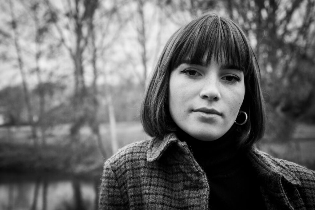léa, photo portrait extérieur noir et blanc, nature, bois, veste carreaux, carré frange, automne - série de photo portait réalisée par Anael Jourdain Photographe Amateur Hauts-de-France