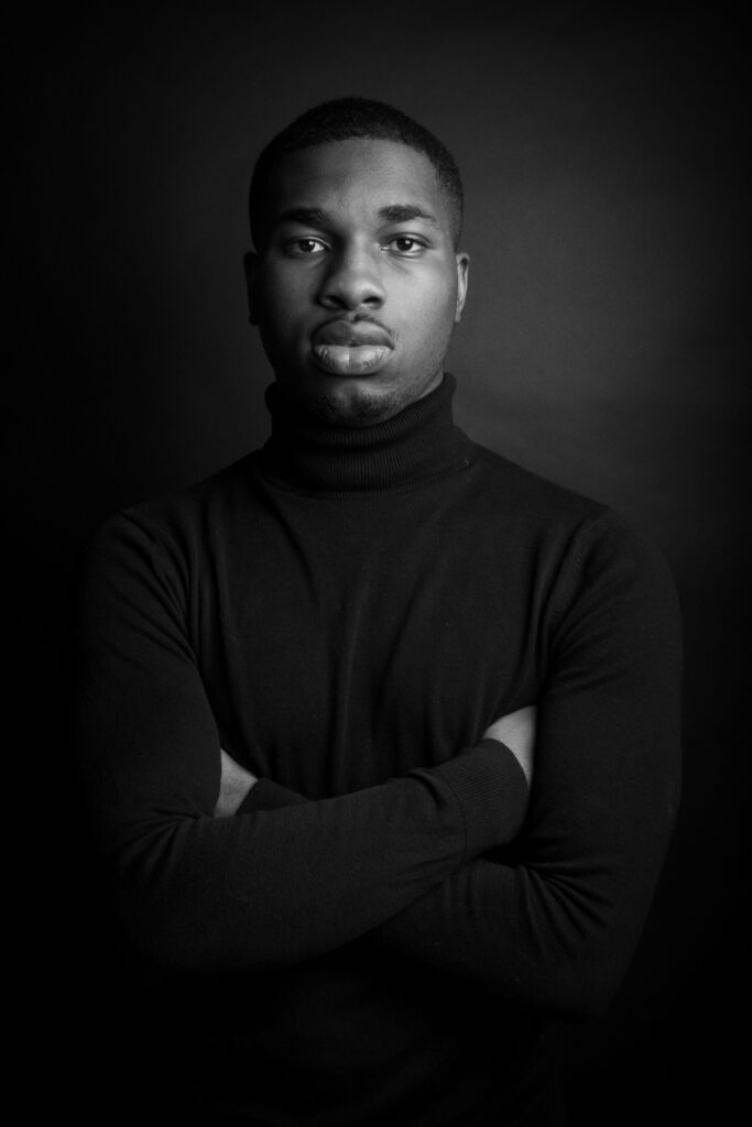 mamad, photo studio noir et blanc, jeune homme noir, bras croisés, col roulé - série de photo portait réalisée par Anael Jourdain Photographe Amateur Hauts-de-France