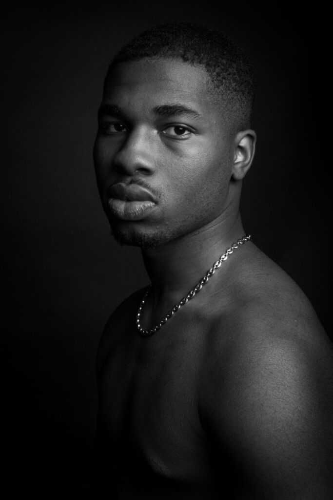 mamad, photo studio noir et blanc, torse nu, jeune homme noir, regard profond - série de photo portait réalisée par Anael Jourdain Photographe Amateur Hauts-de-France