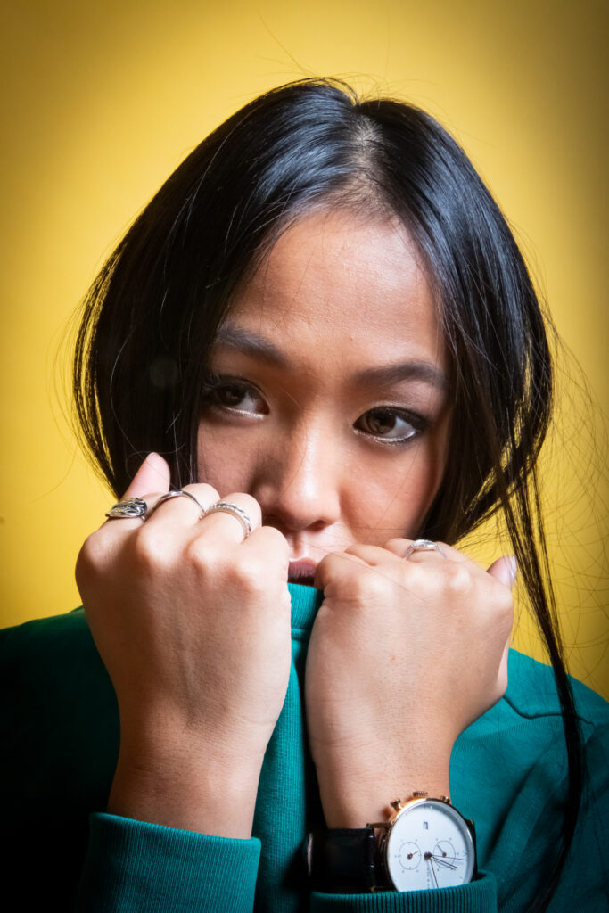 victoire, portrait studio, fond jaune et pull vert, regard de côté, montre photo couleur format portrait - série de photo portait réalisée par Anael Jourdain Photographe Amateur Hauts-de-France